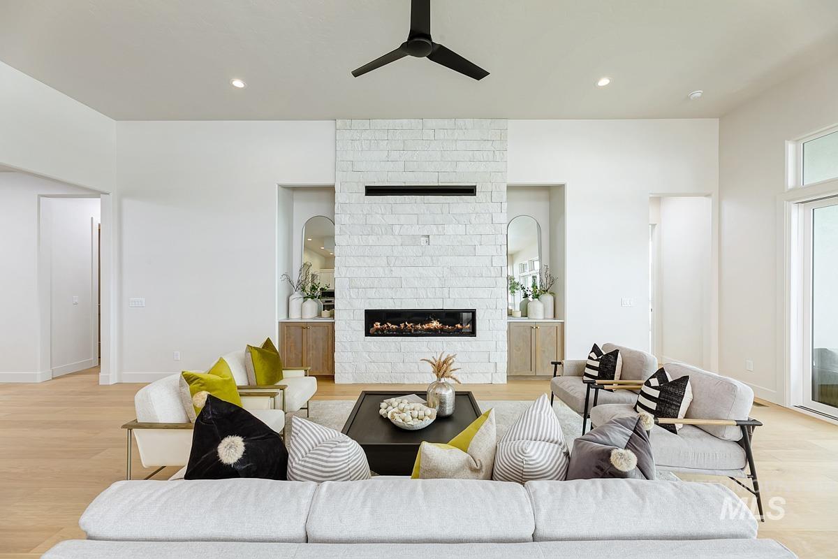 Living area with light wood-style floors, a ceiling fan, a fireplace, and recessed lighting