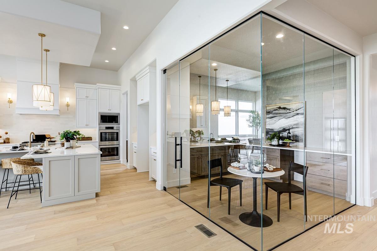 Kitchen with light wood-style floors, white cabinets, a breakfast bar, decorative light fixtures, and light stone countertops