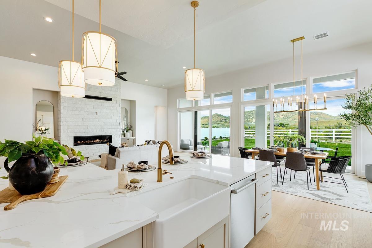 Kitchen with light stone counters, a glass covered fireplace, pendant lighting, light wood finished floors, and white cabinets