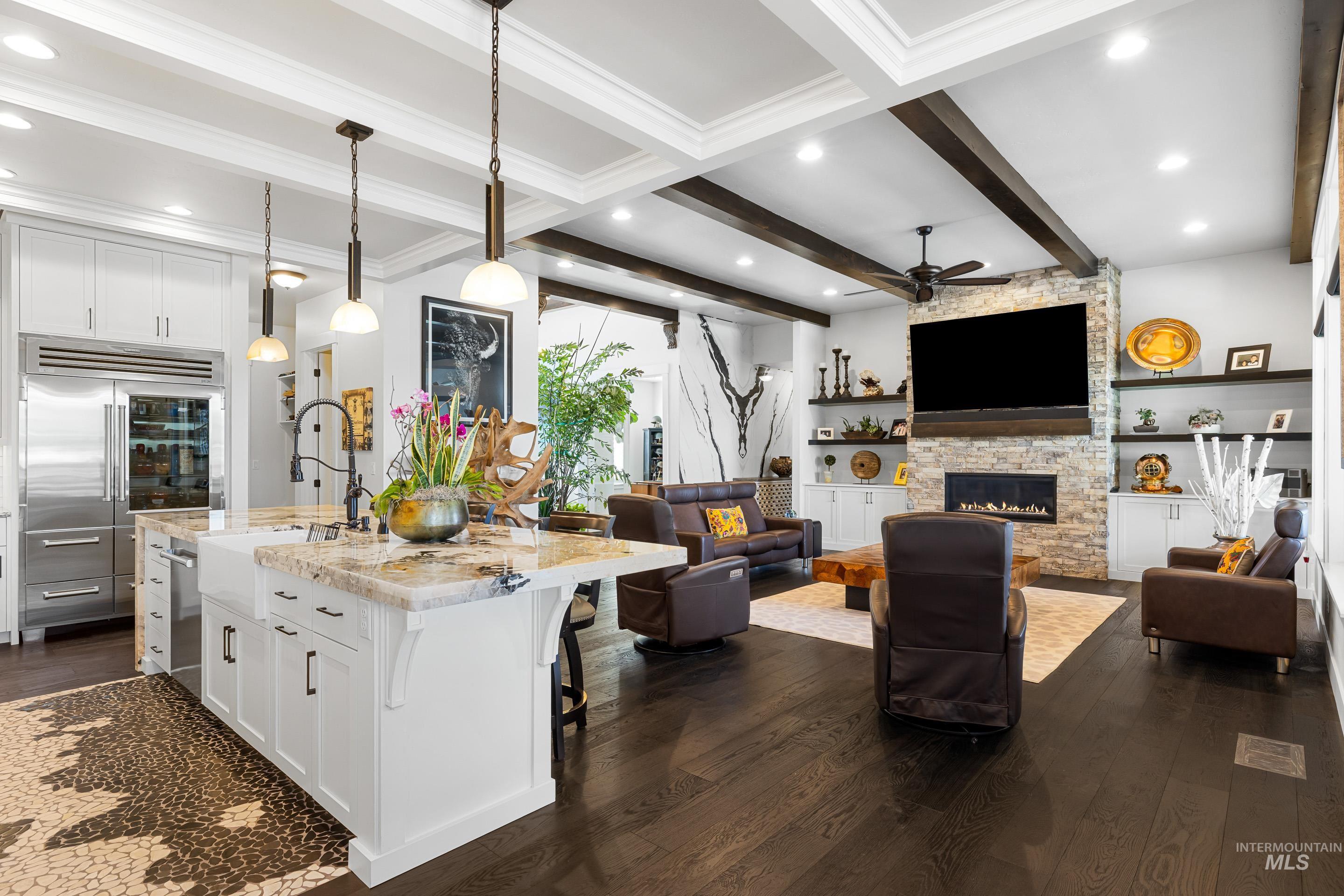 Kitchen with white cabinets, light stone counters, a kitchen bar, beamed ceiling, and pendant lighting