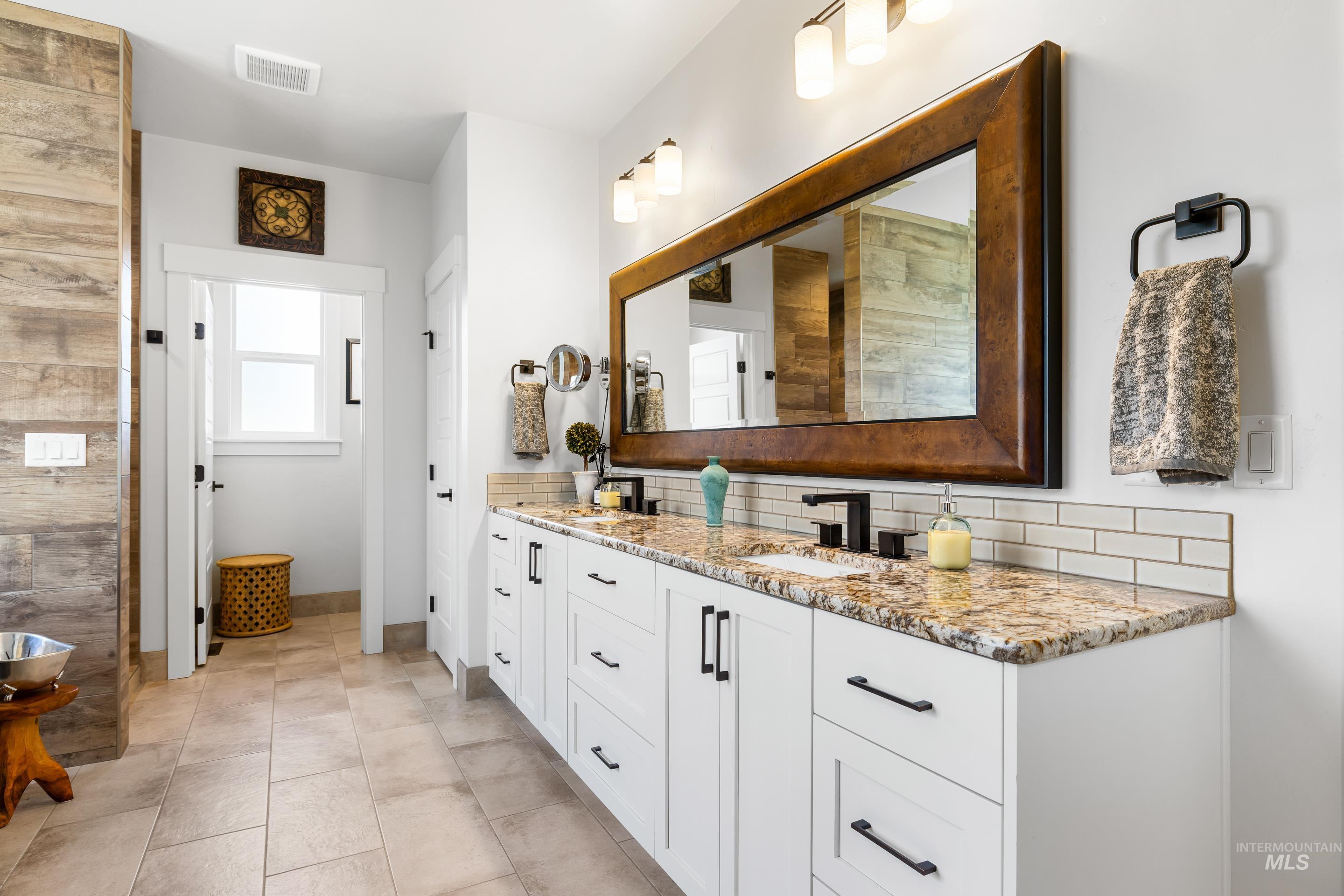 Bathroom with double vanity, backsplash, and light tile patterned floors