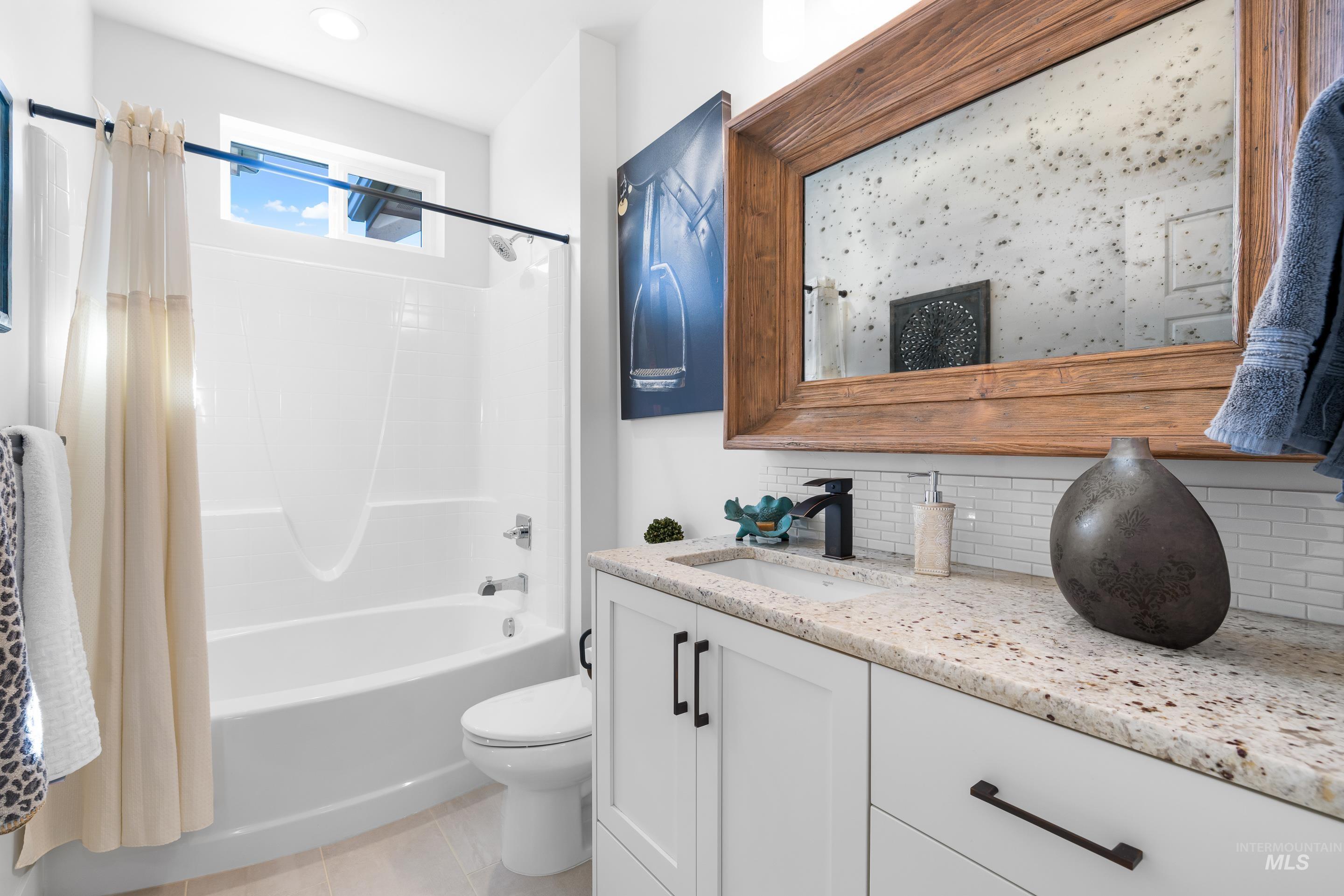 Bathroom with shower / bathtub combination with curtain, decorative backsplash, vanity, and light tile patterned flooring