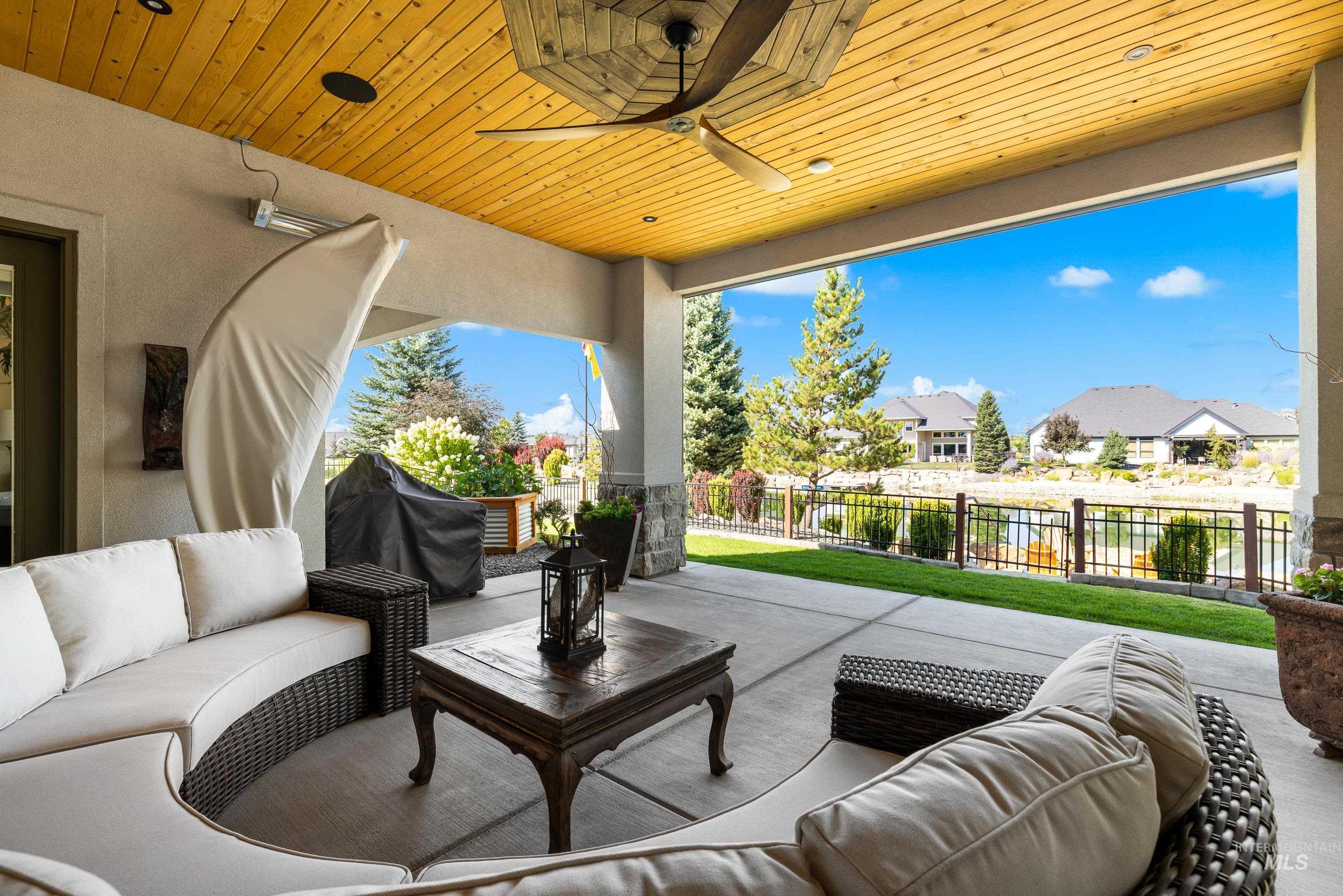 Fenced backyard featuring outdoor lounge area, a patio, a grill, a ceiling fan, and a residential view