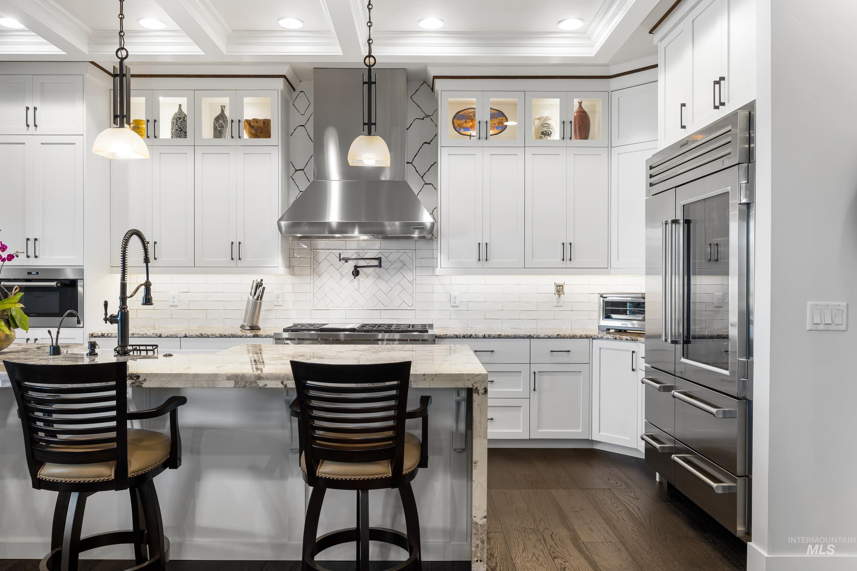 Kitchen featuring glass insert cabinets, appliances with stainless steel finishes, decorative light fixtures, white cabinets, and recessed lighting