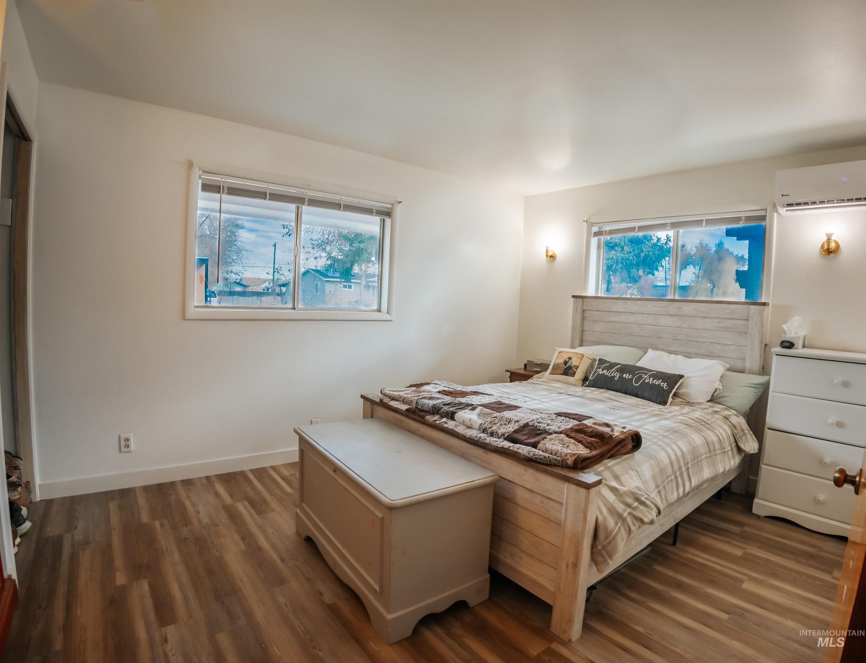 Bedroom with wood finished floors and a wall mounted air conditioner