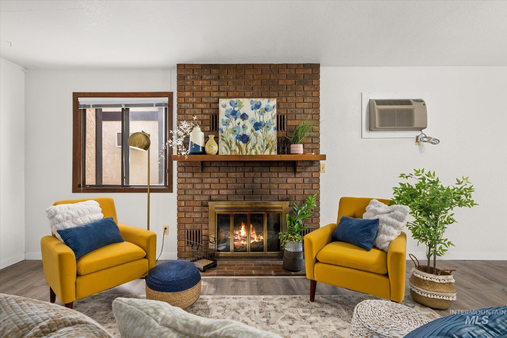 Living room with wood finished floors, a fireplace, and a wall mounted AC