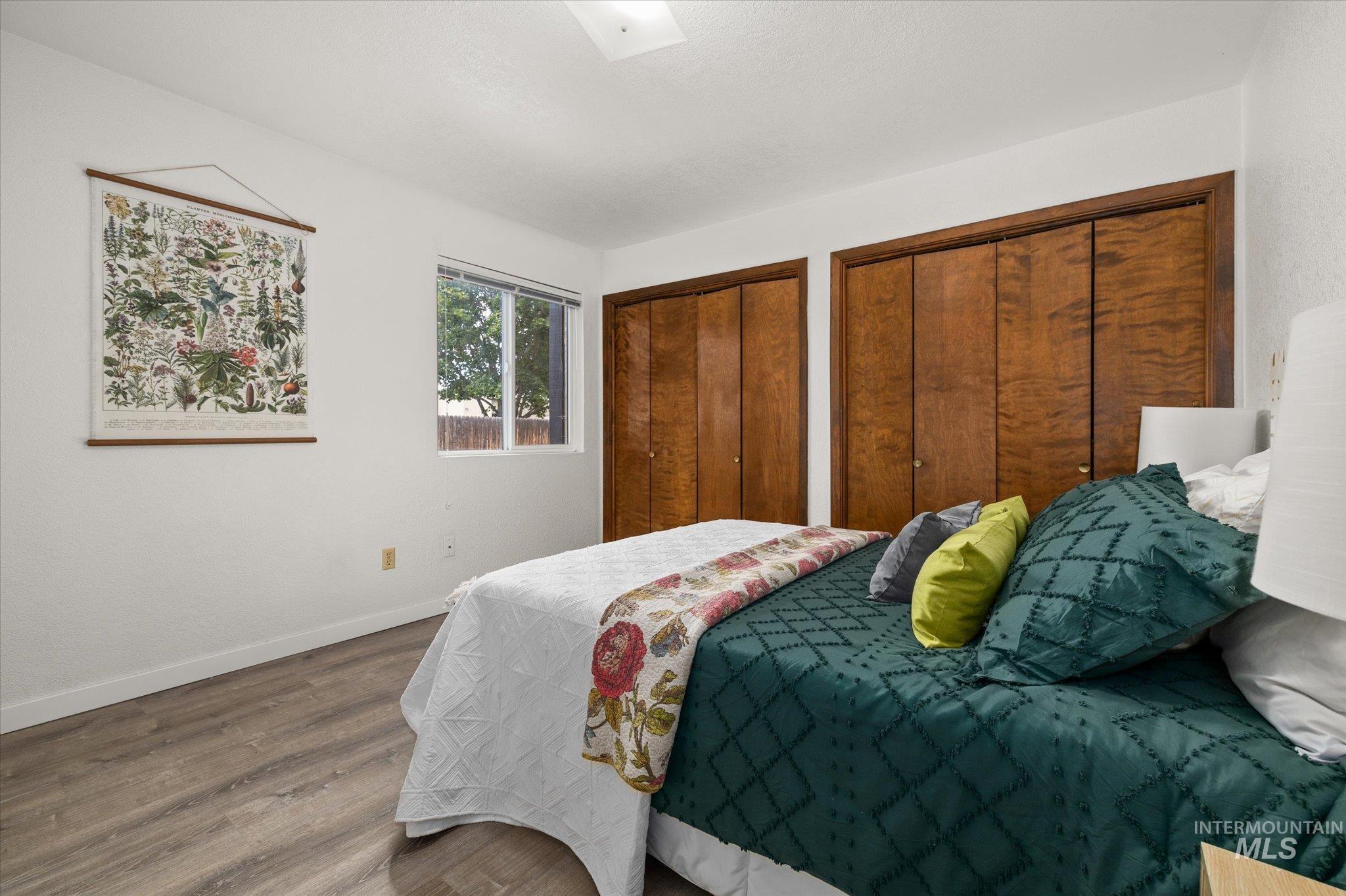 Bedroom with wood finished floors and two closets