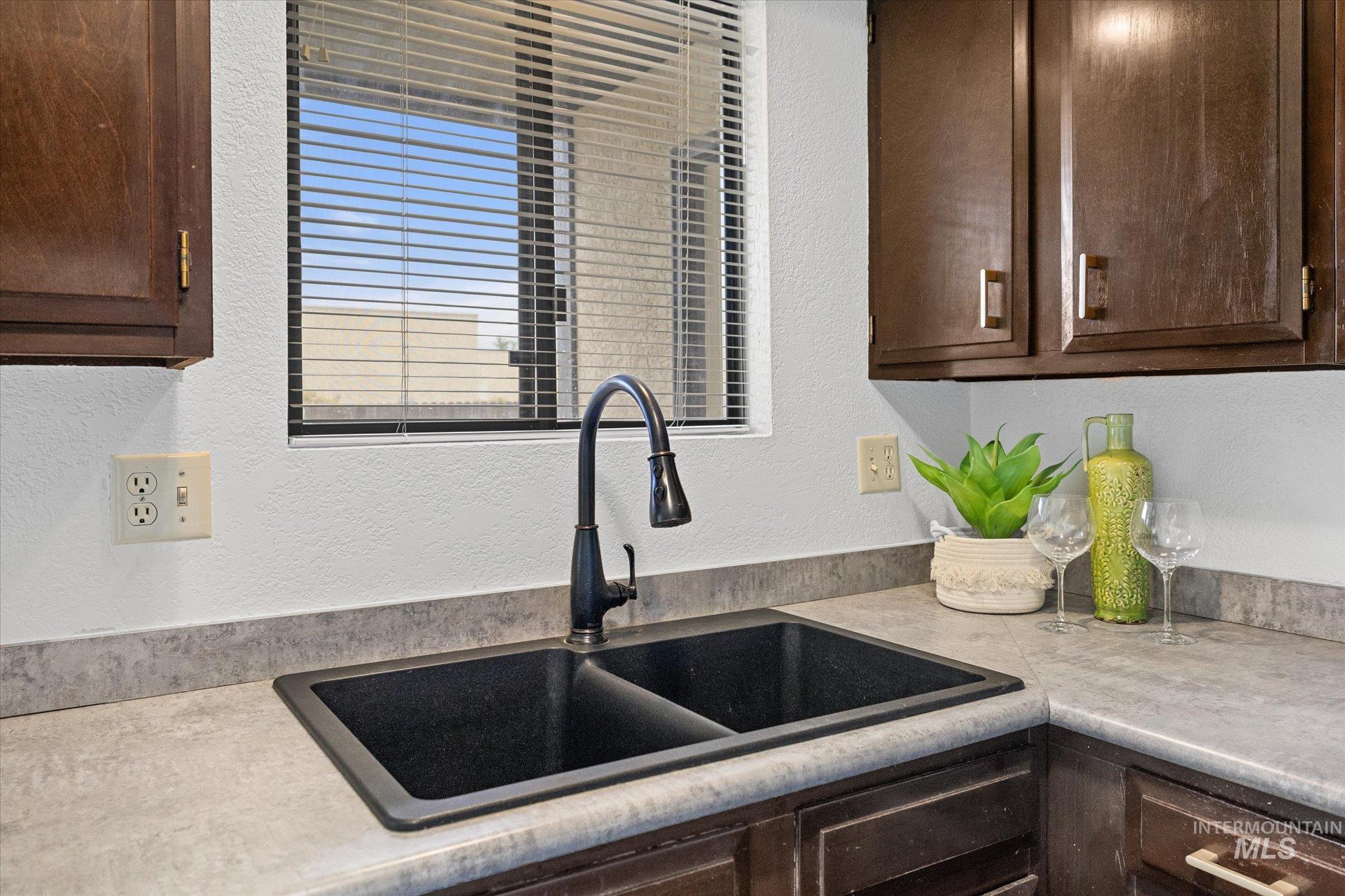 Kitchen featuring a textured wall, dark brown cabinets, and light countertops