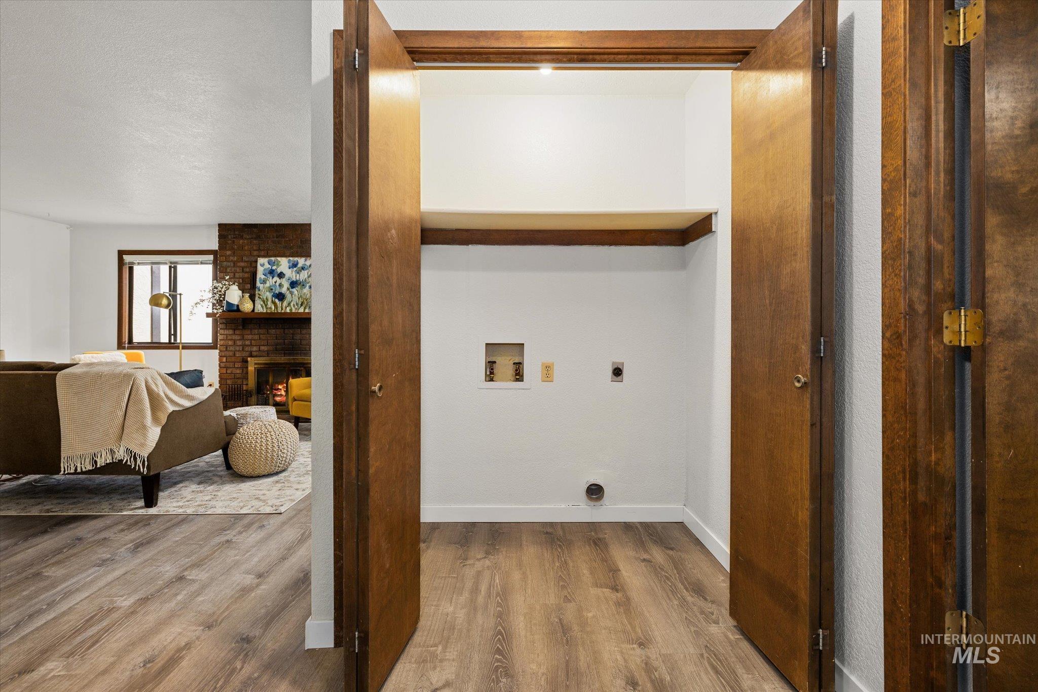 Laundry room featuring hookup for an electric dryer, washer hookup, wood finished floors, and a fireplace