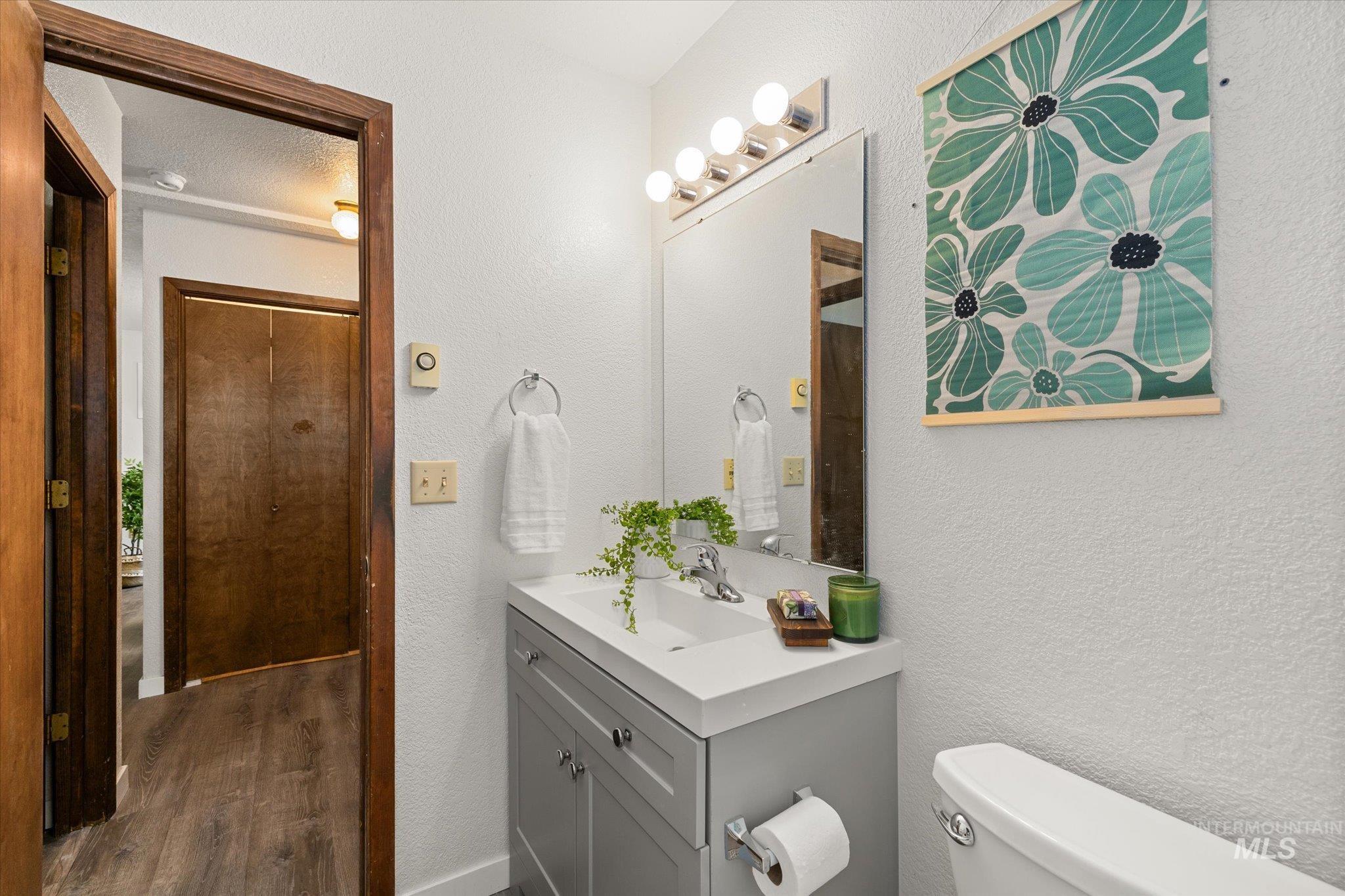 Bathroom with a textured wall, vanity, and wood finished floors