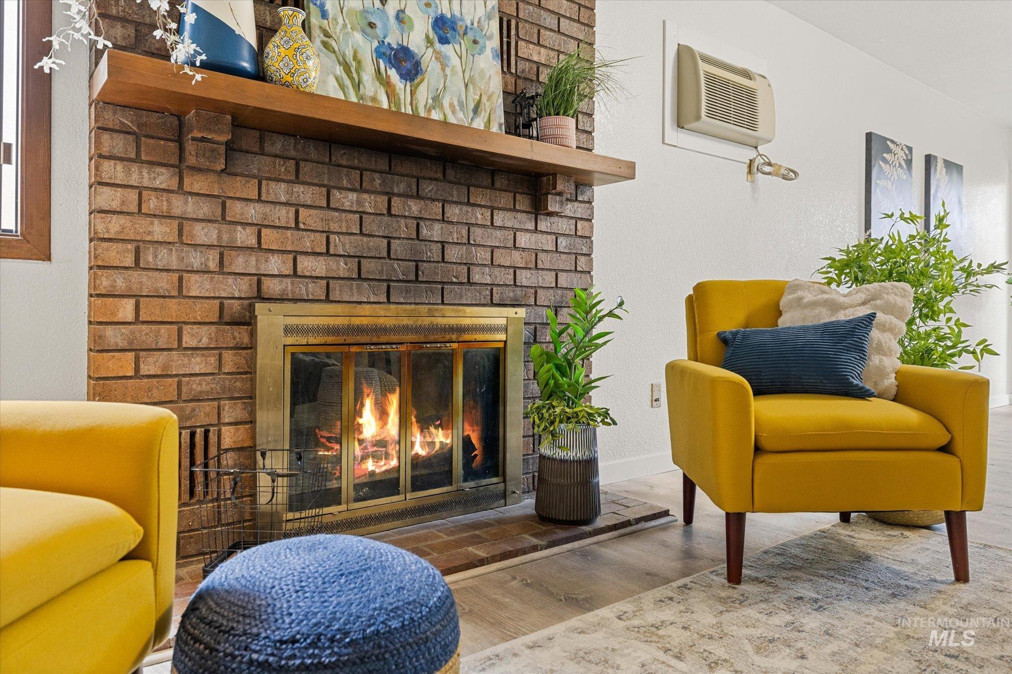 Living area featuring wood finished floors, a fireplace, and a wall unit AC