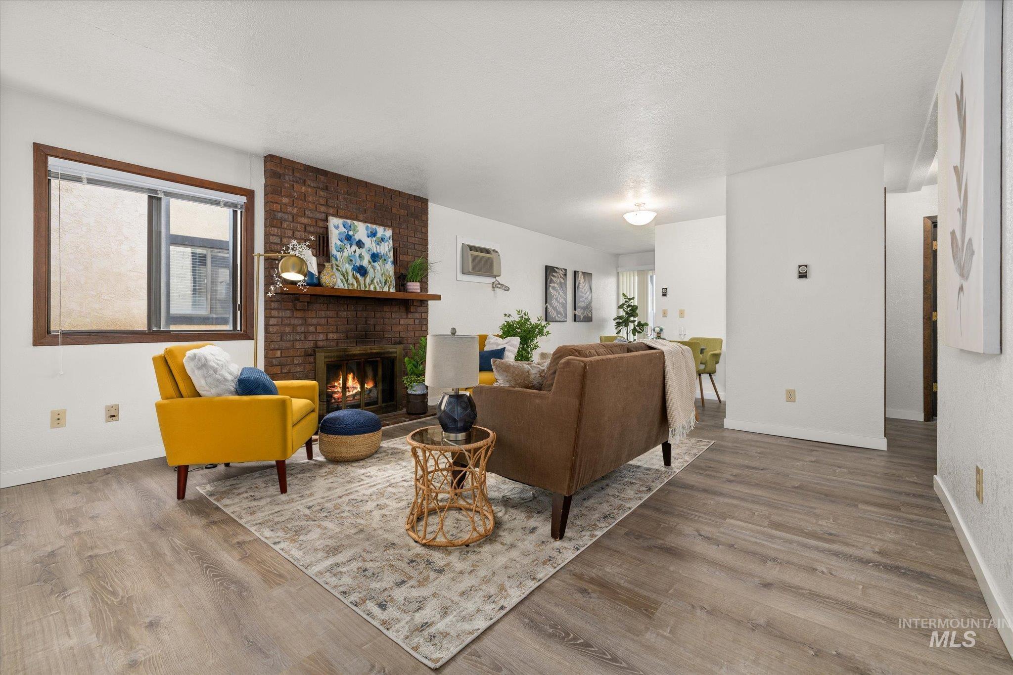 Living area featuring a fireplace, wood finished floors, and a wall mounted air conditioner