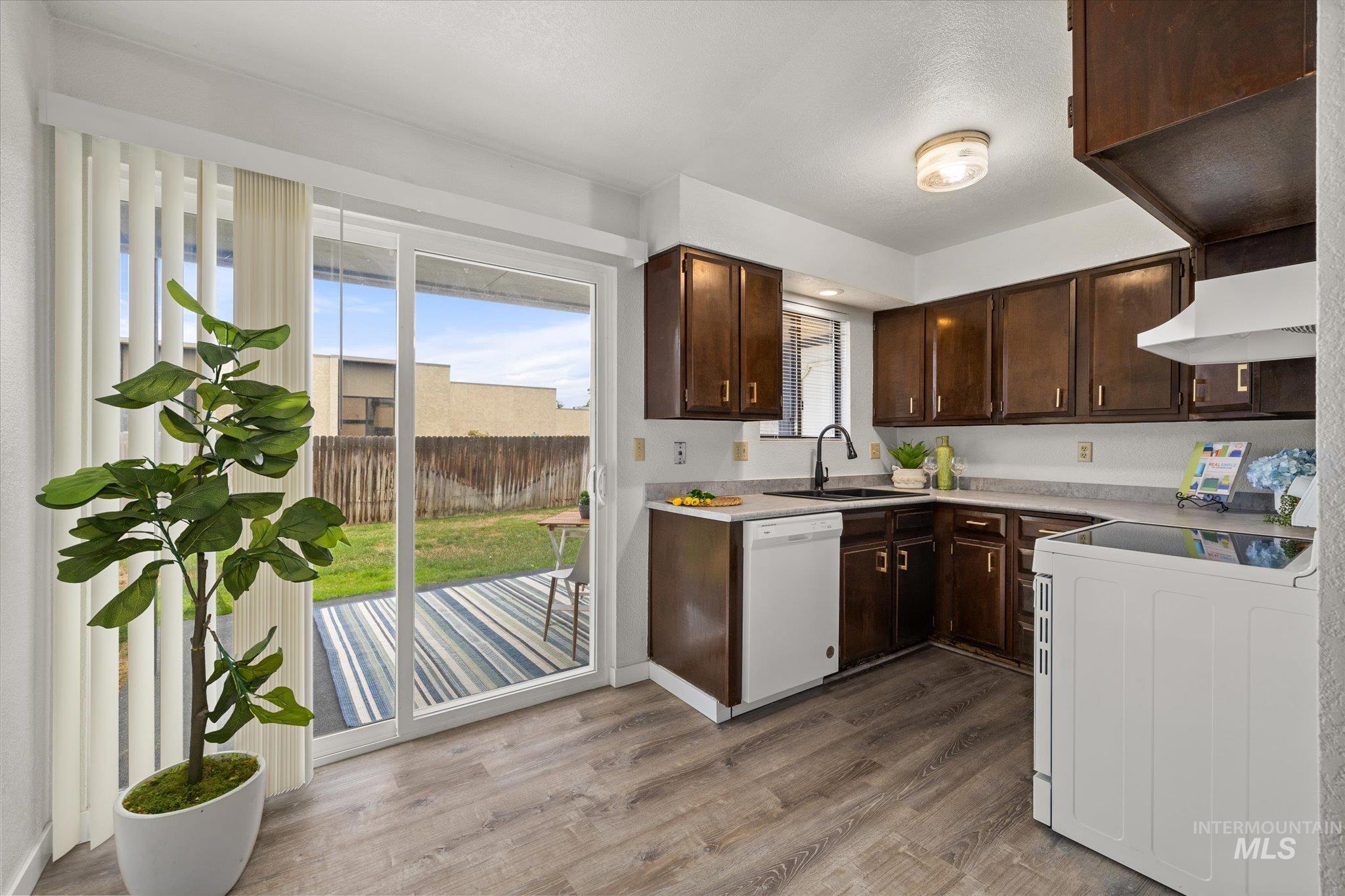 Kitchen with stove, dark brown cabinets, light wood-style floors, light countertops, and custom range hood