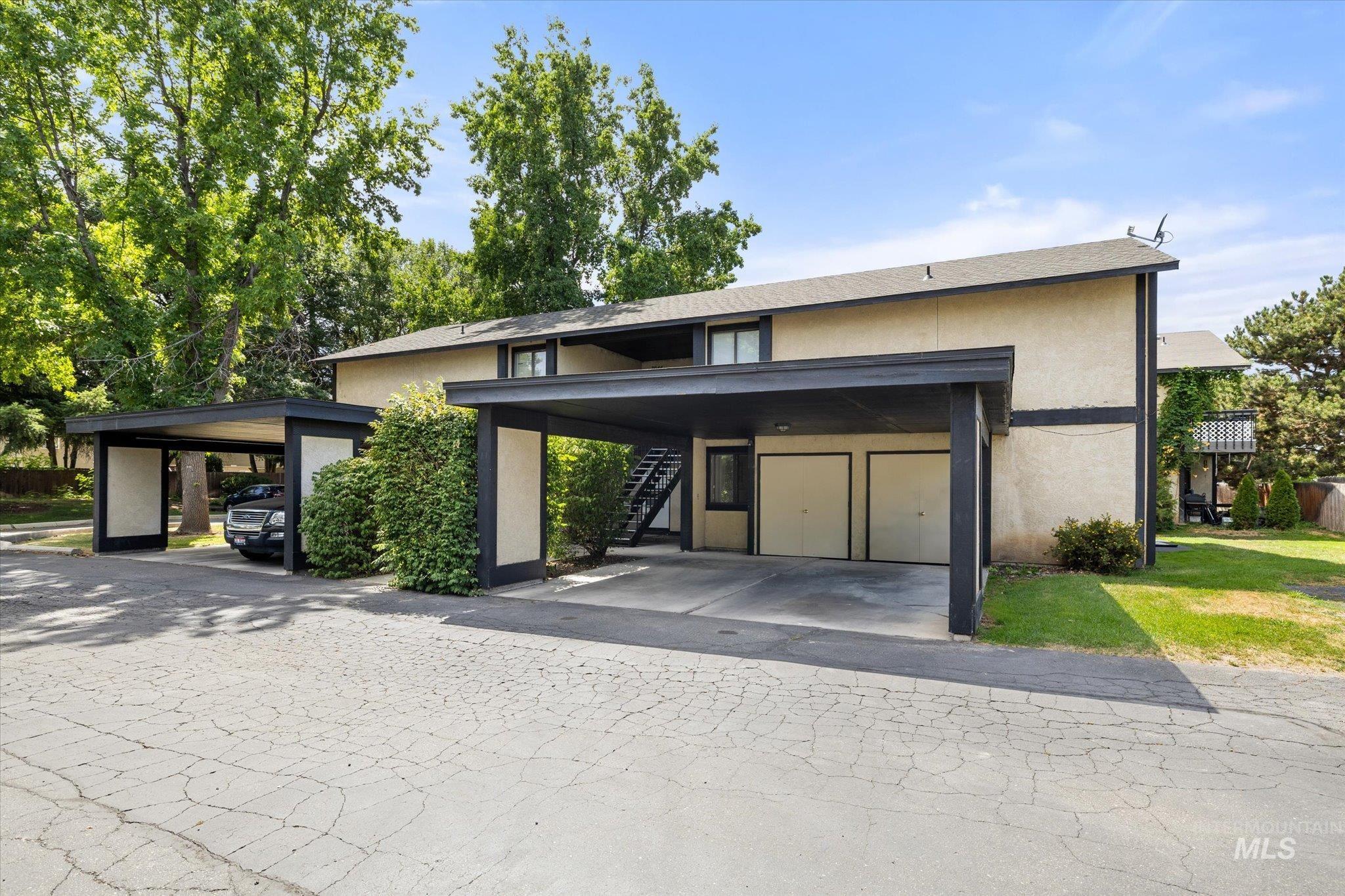 View of front of property featuring stairway, stucco siding, and covered parking