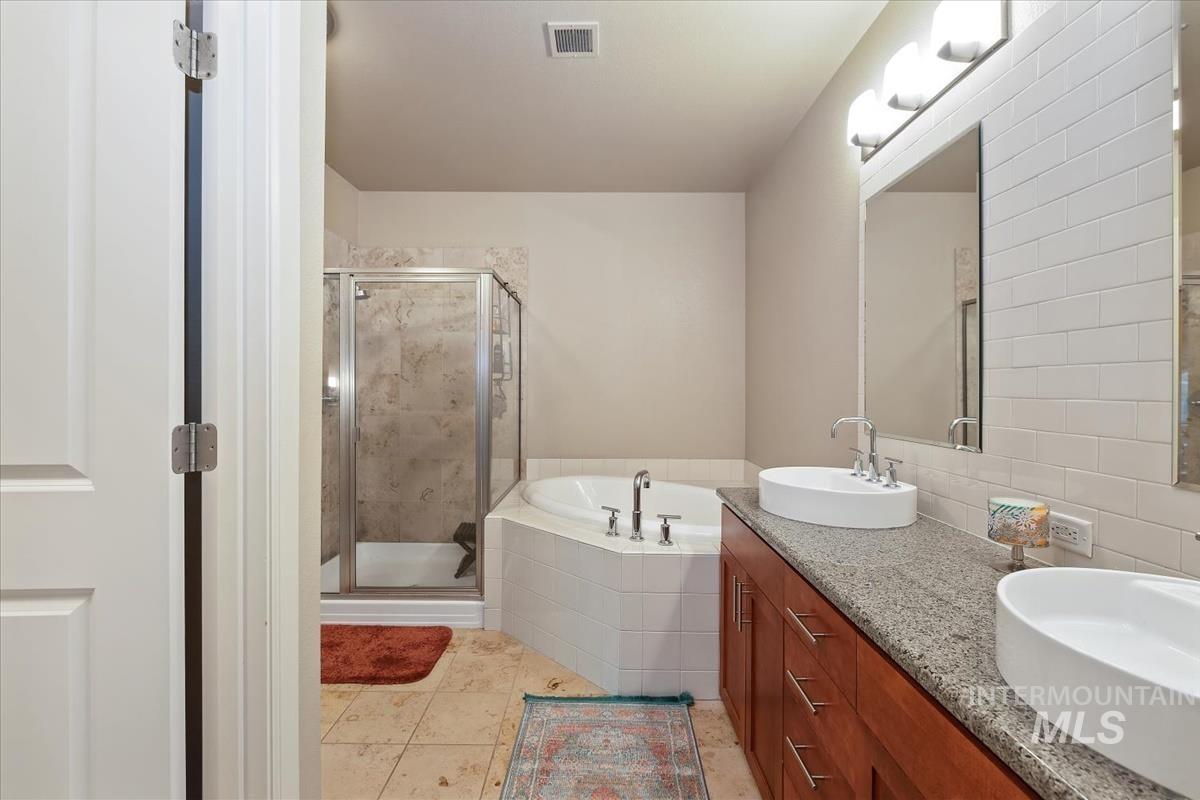 Full bath with a shower stall, a garden tub, double vanity, and light tile patterned floors