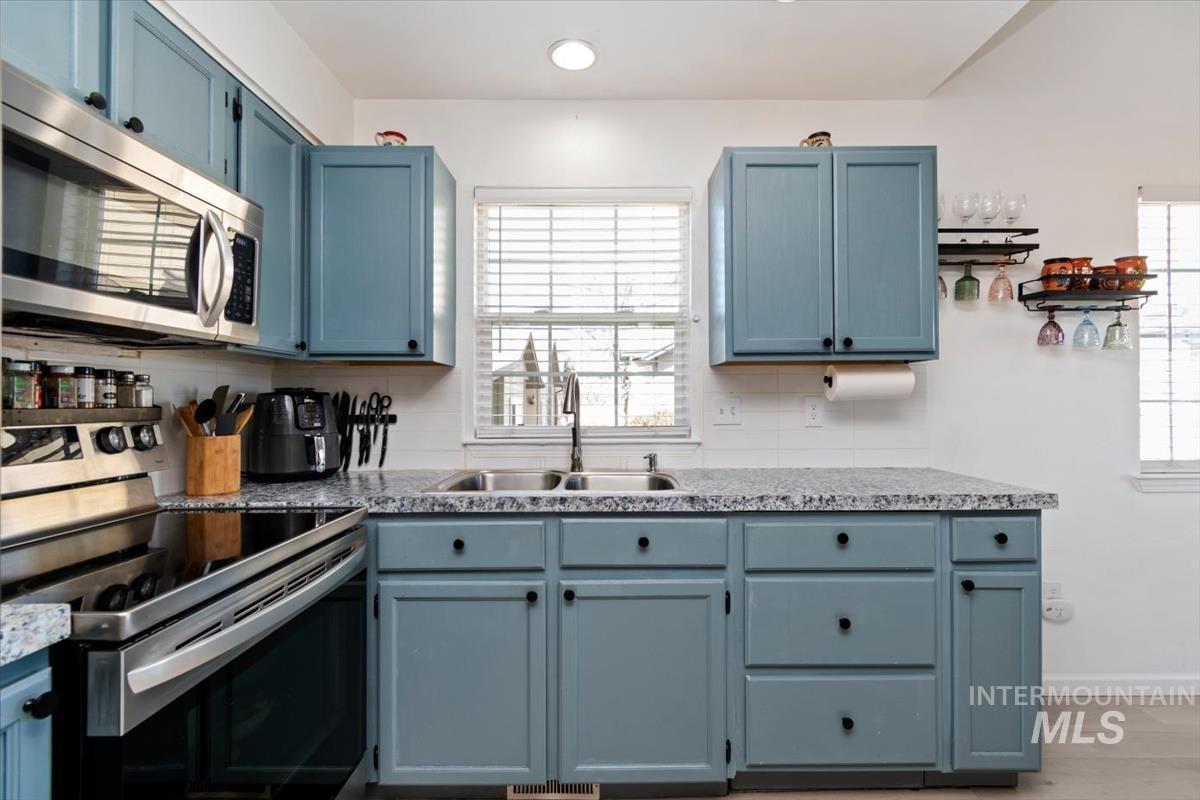 Kitchen featuring blue cabinetry, stainless steel appliances, and light countertops