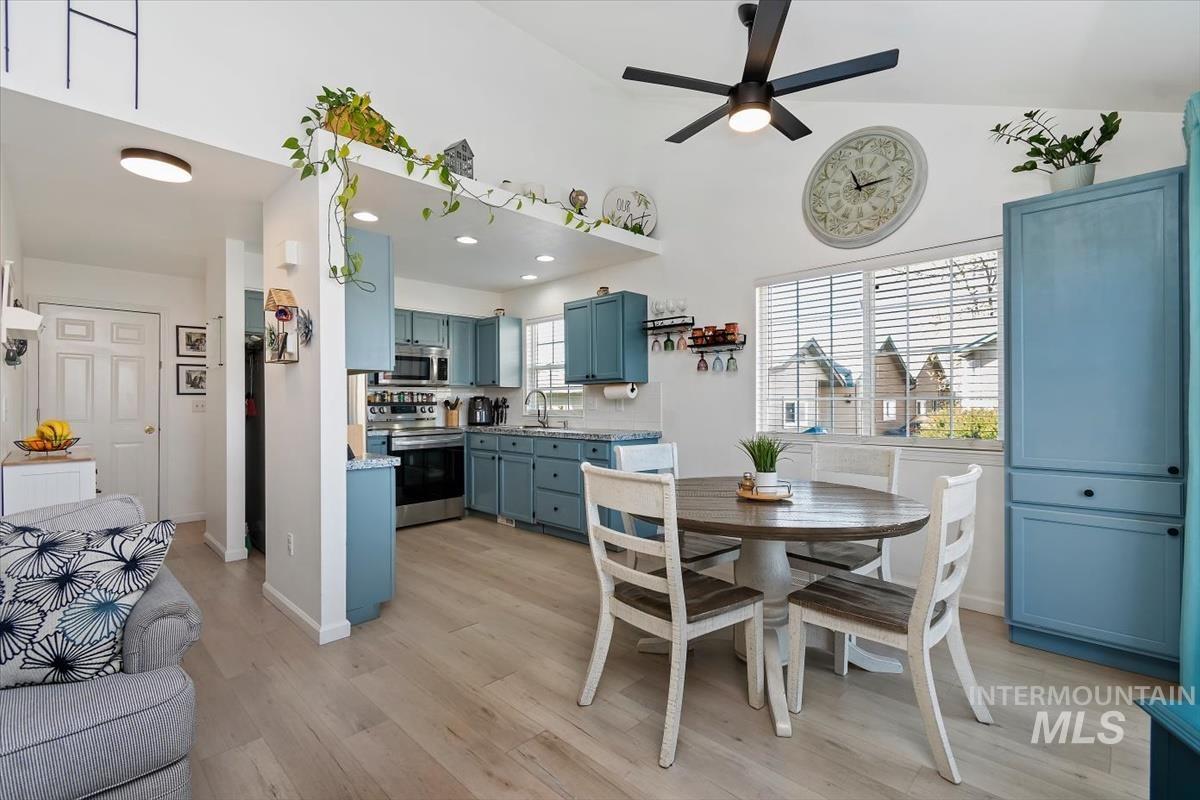 Dining area with light wood finished floors, a ceiling fan, and a high ceiling