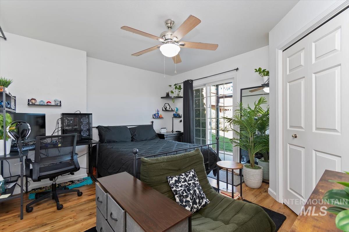 Bedroom featuring light wood-style flooring, ceiling fan, an office area, and a closet