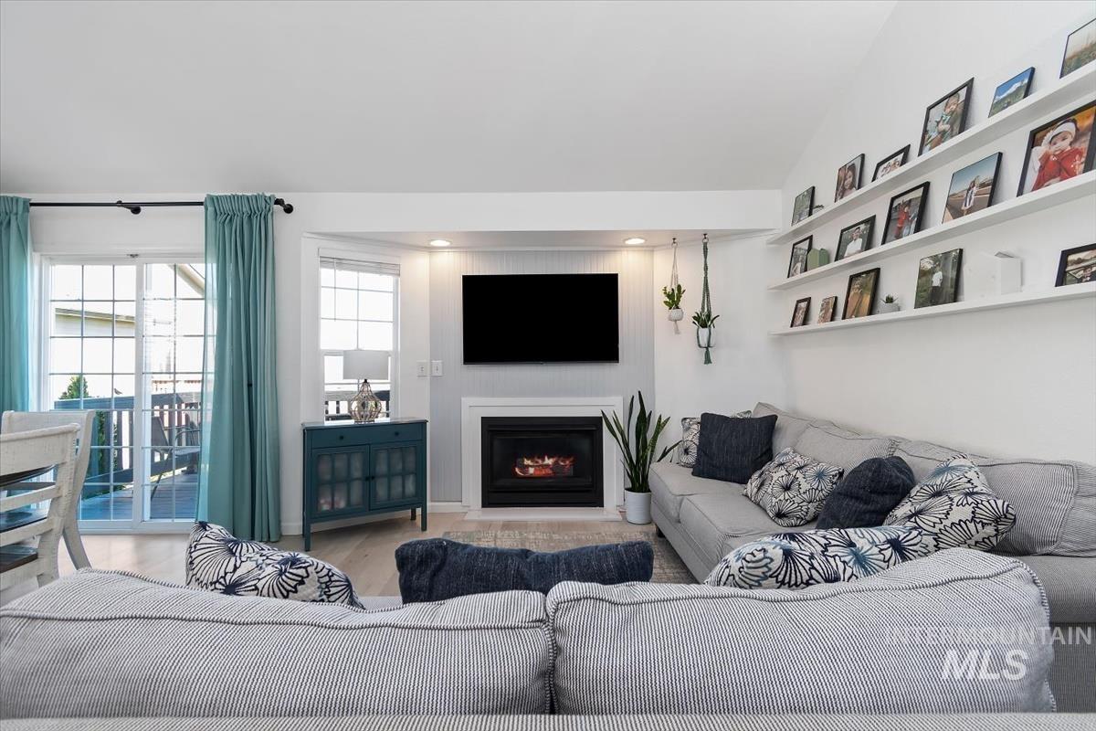 Living room with wood finished floors and a warm lit fireplace