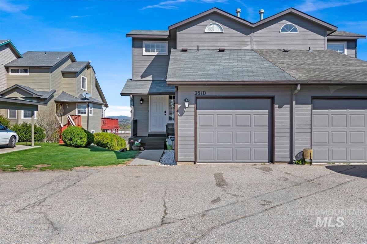 View of front of house with a shingled roof, a garage, a front yard, and driveway
