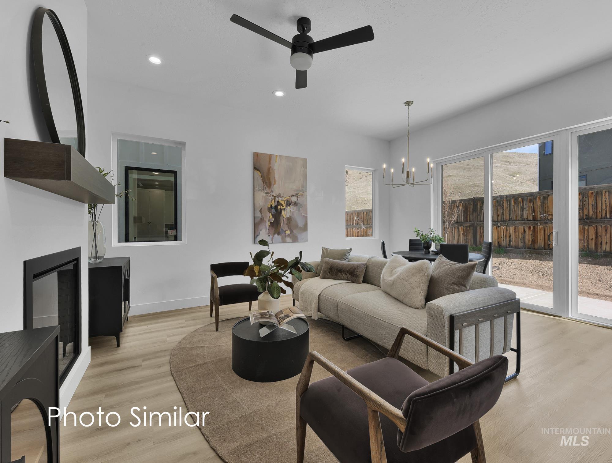 Open-concept living space featuring wood-finish flooring, a modern fireplace with a dark mantel, and recessed lighting