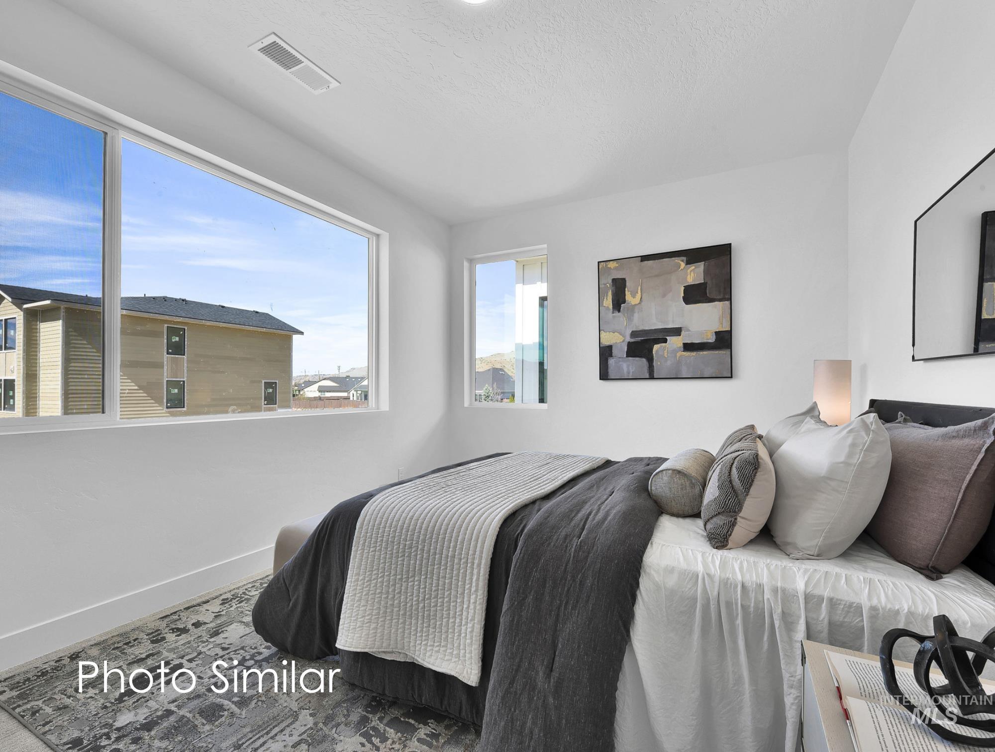 Bright bedroom featuring a large picture window, a secondary window, white walls, and recessed lighting