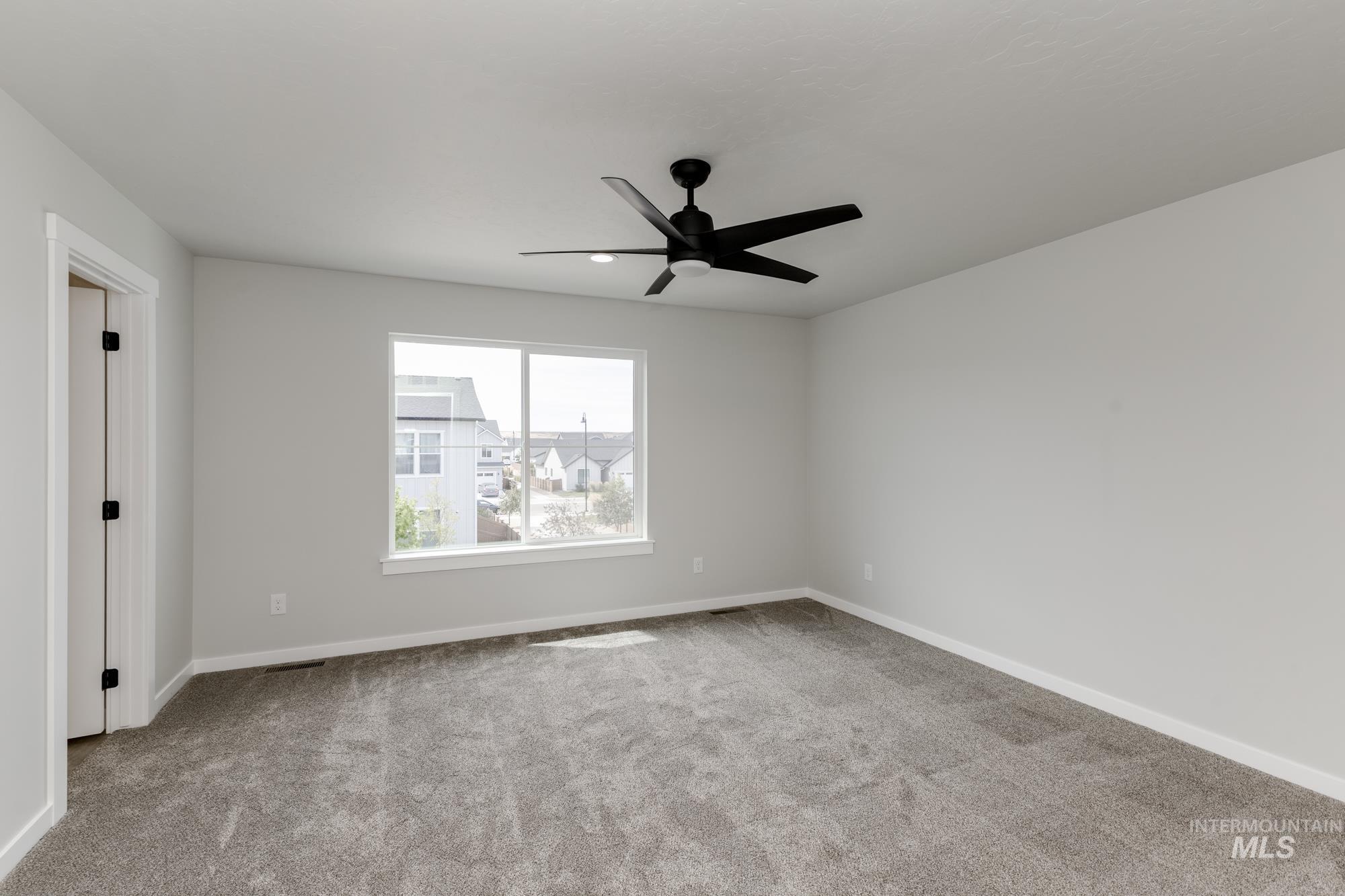 Spare room featuring light colored carpet and a ceiling fan