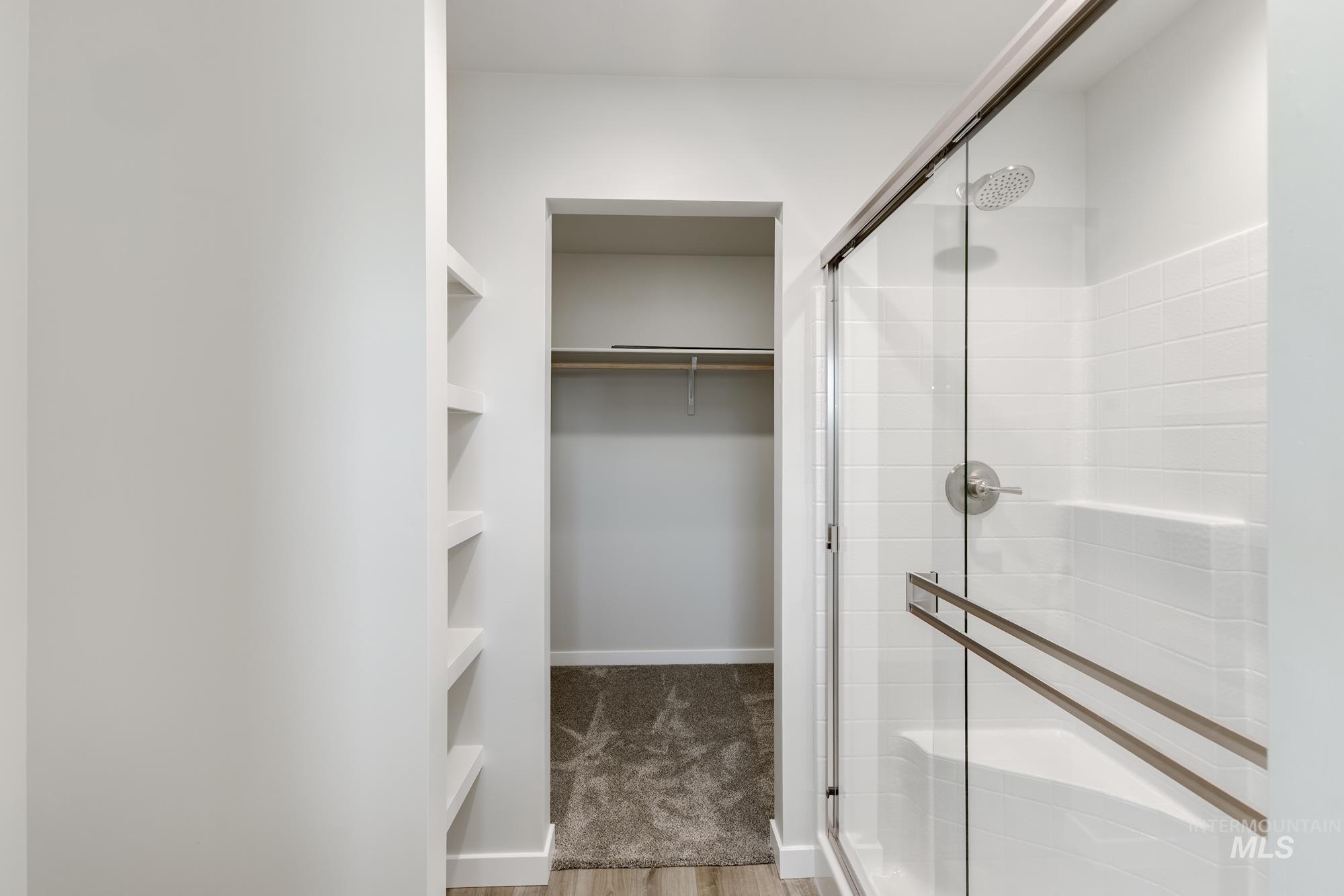 Full bathroom featuring a walk in closet, a shower stall, and light wood-style flooring
