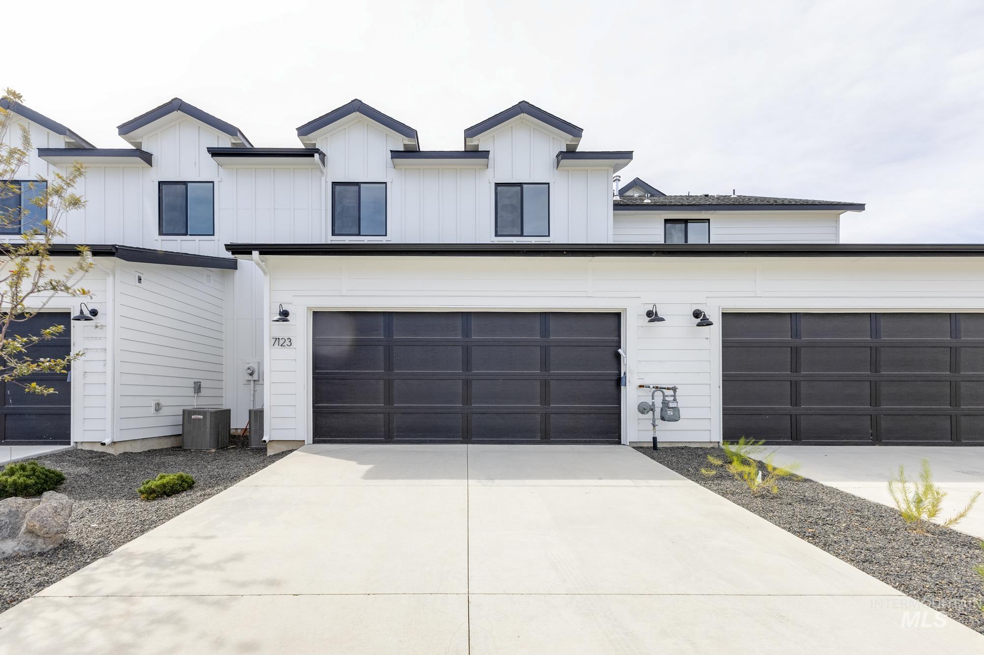 Modern farmhouse with concrete driveway, an attached garage, and board and batten siding