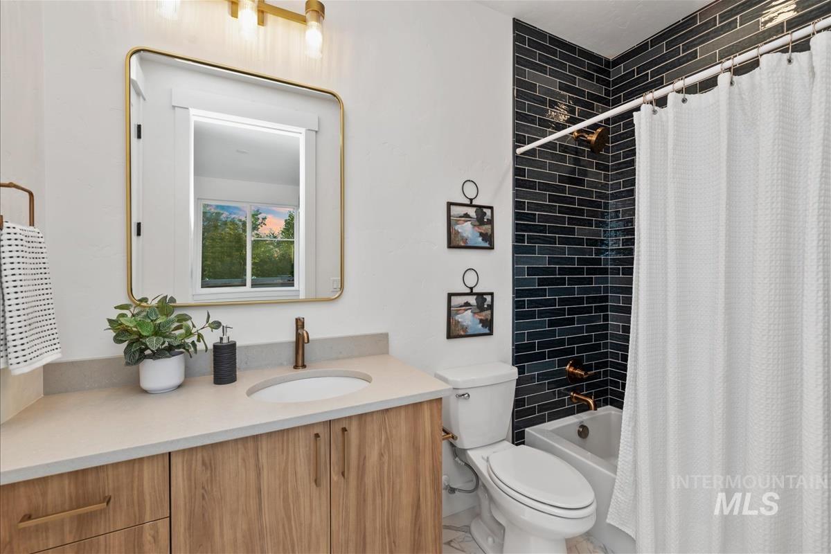 Bathroom featuring a wood-finish vanity with an undermount sink, a light-toned countertop, and a rectangular mirror