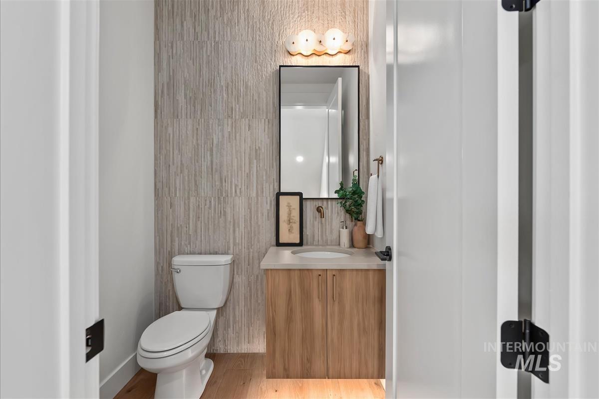 Powder room featuring a wood-finish vanity with an undermount sink, a framed mirror, and a sconce light fixture