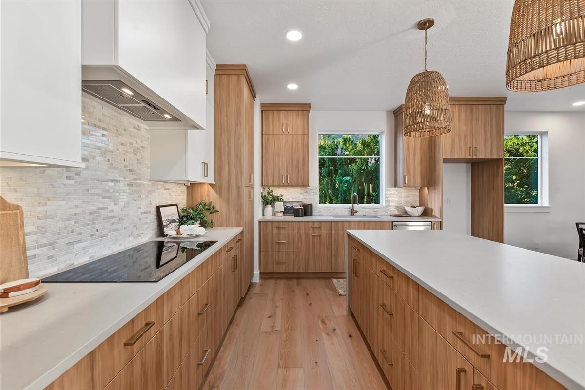 Kitchen featuring light wood-finish cabinetry, white countertops, and a full-height tile backsplash