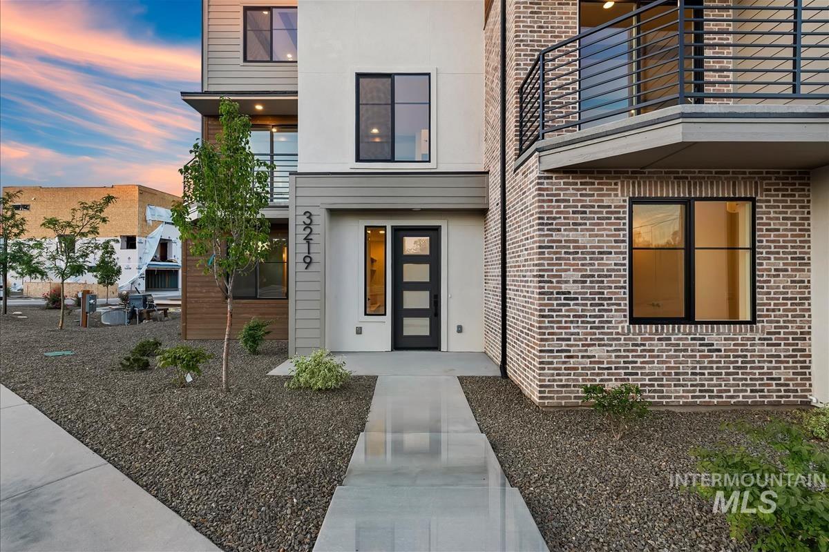 Modern multi-story exterior featuring a prominent brick facade and a multi-pane glass entry door