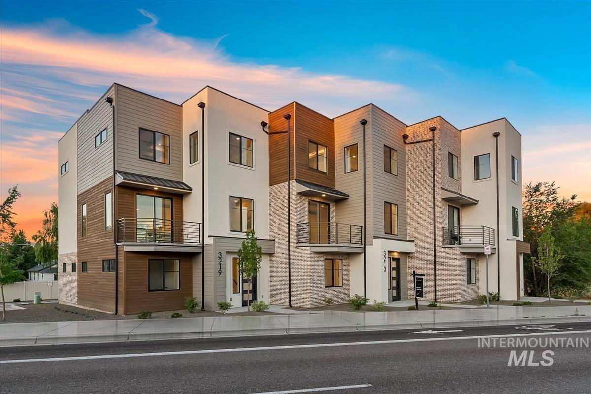 Modern townhome exterior featuring multi-textured facade with stucco, horizontal wood-finish siding, and brick accents
