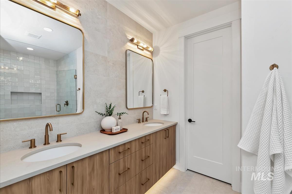 Double vanity with undermount sinks and bronze-finish faucets set against a light-toned countertop