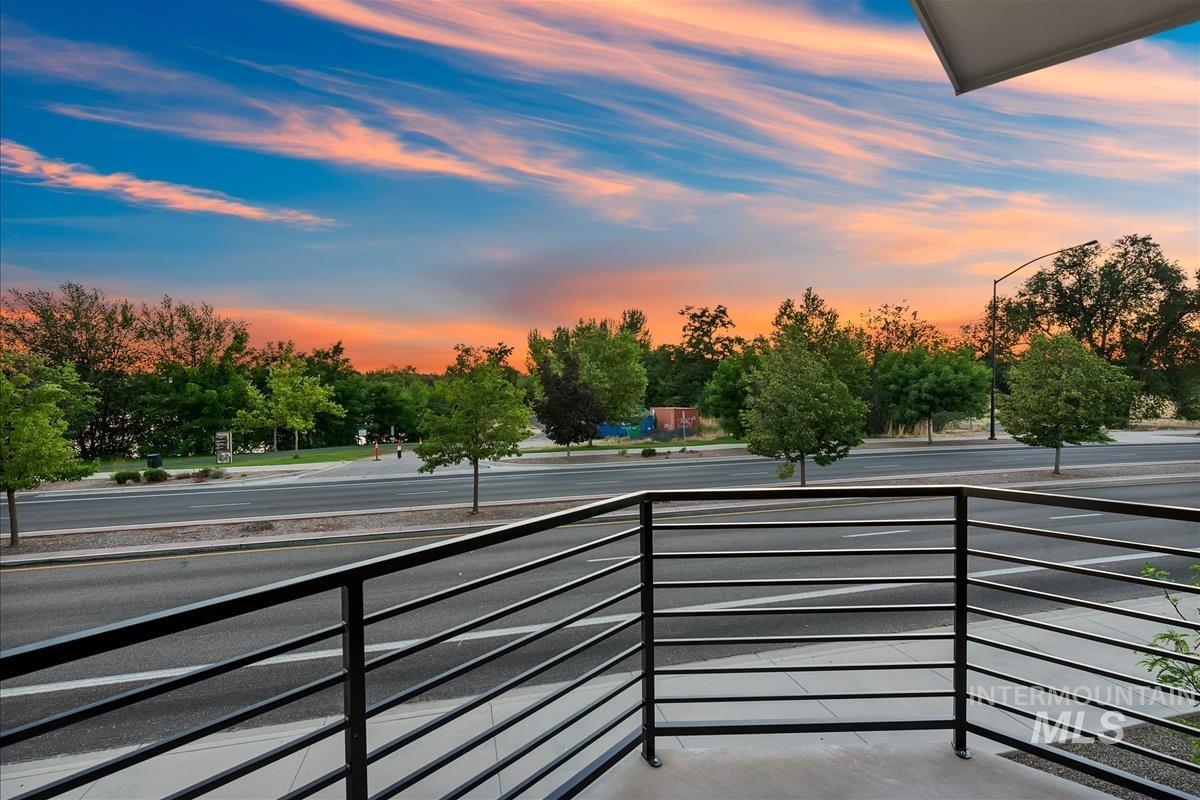 Balcony with metal railing overlooking a street and mature trees
