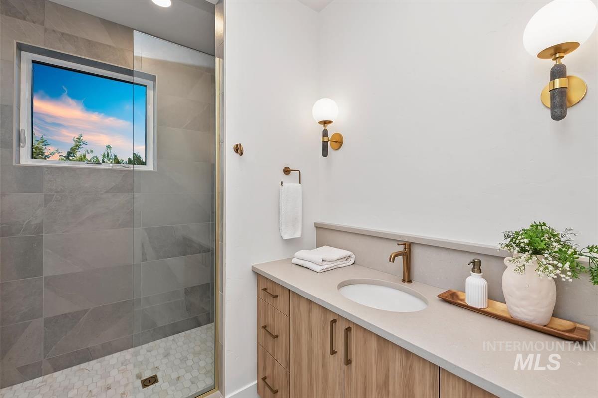 Shower with large format gray tile walls and white hexagonal tile flooring