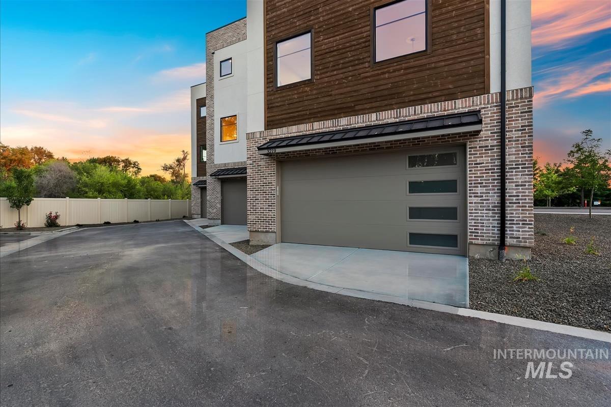 Contemporary exterior featuring brick and horizontal wood paneling, modern garage doors with frosted glass panels, and a concrete driveway