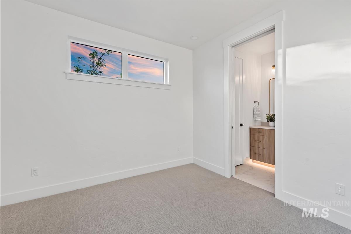 Carpeted room featuring a high transom window, crisp white walls, and a recessed doorway