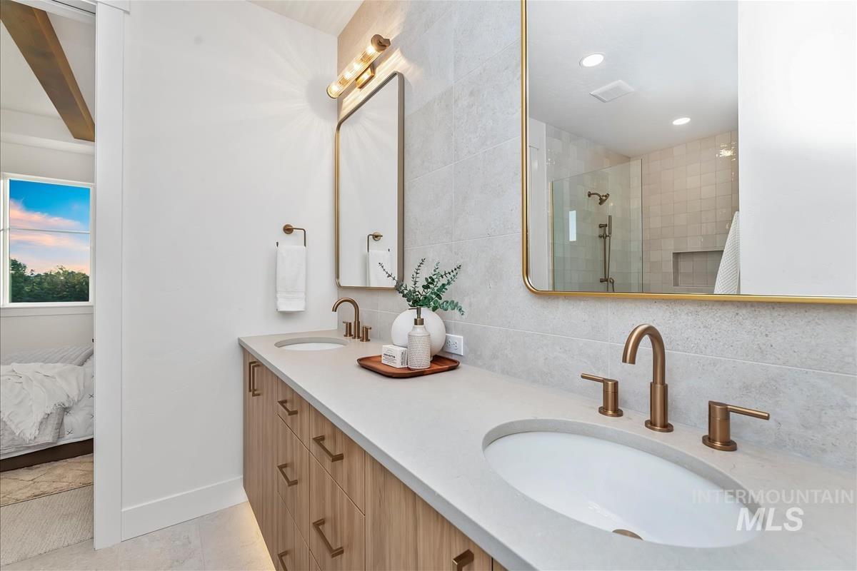 Dual vanity with light wood-finish cabinetry, integrated sinks, and bronze-tone fixtures
