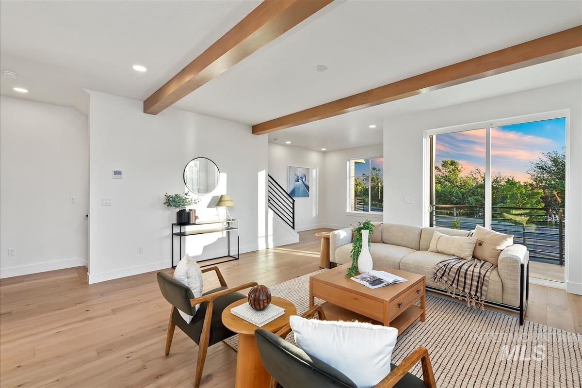 Open-concept living space featuring wood-finish flooring, exposed wood ceiling beams, and recessed lighting