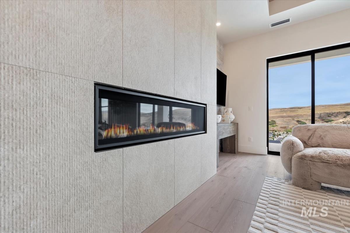 Living area featuring light wood-style flooring, a multi sided fireplace, and recessed lighting