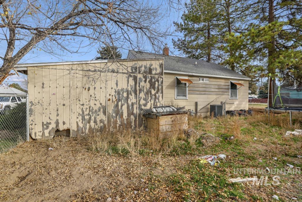 View of side of home with a trampoline, a chimney, and roof with shingles