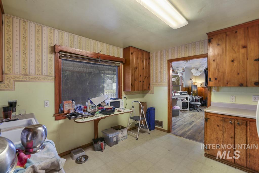 Kitchen with light floors, brown cabinetry, light countertops, white microwave, and an office area