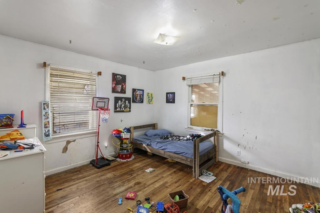 Bedroom with dark wood finished floors and baseboards