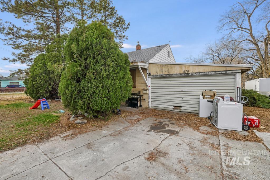 View of side of home with concrete driveway and a chimney