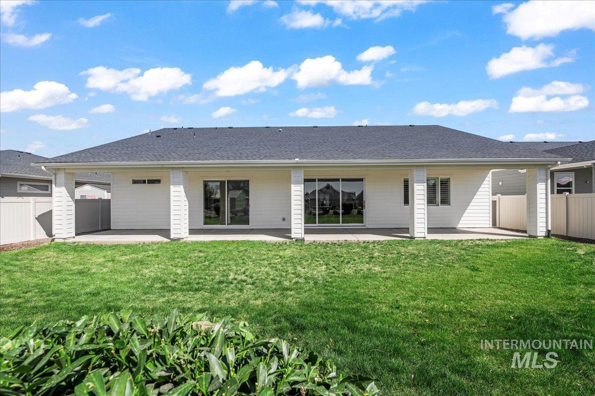 Rear view of house featuring a patio area and a shingled roof