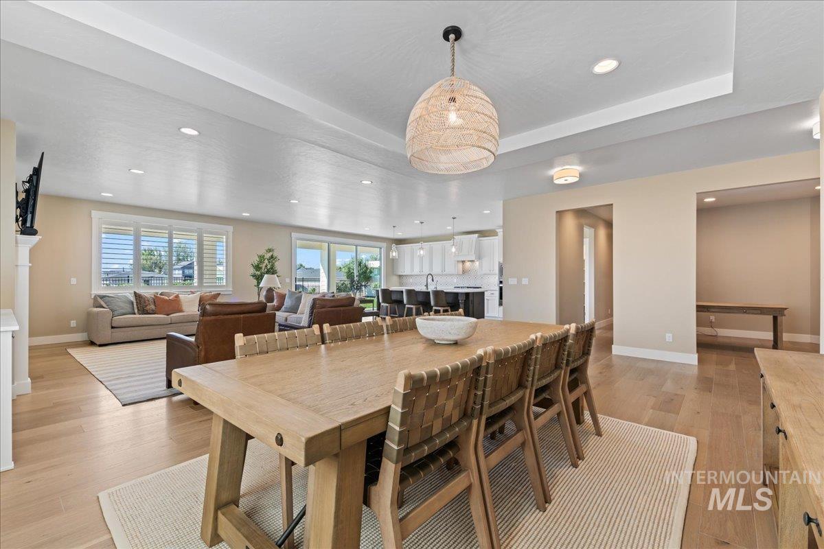 Dining area with recessed lighting, light wood-style floors, and a tray ceiling