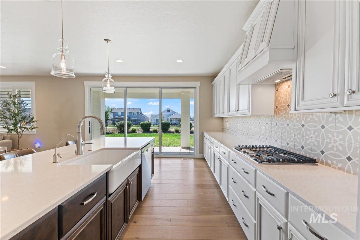 Kitchen with white cabinets, decorative light fixtures, light stone countertops, and recessed lighting