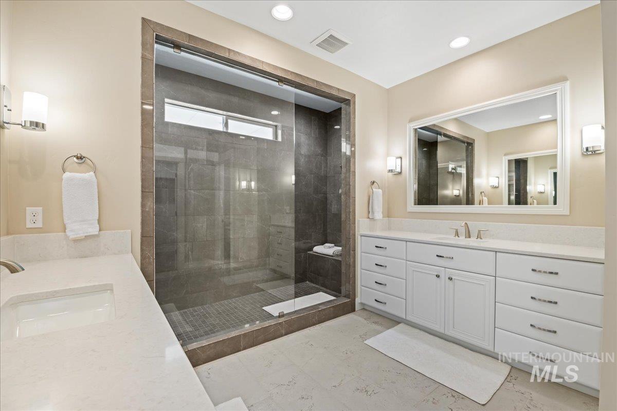 Bathroom featuring two vanities, a walk in shower, and recessed lighting